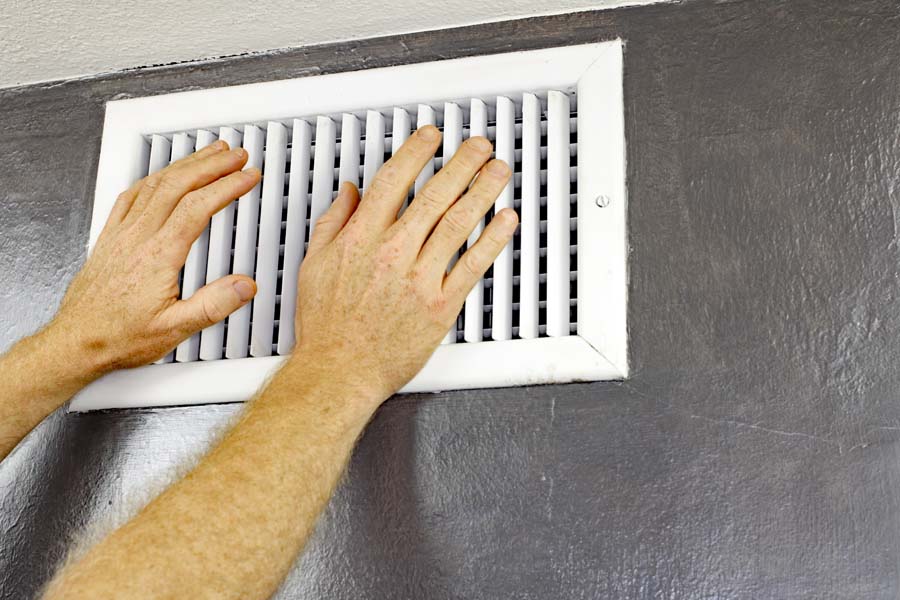 Homeowner feeling wall vent due to AC blowing out hot air.