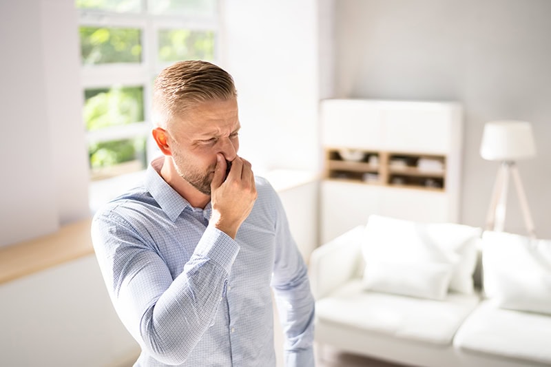 What’s That Smell Coming From My AC at Startup? Photo of a man holding his nose due to odor.