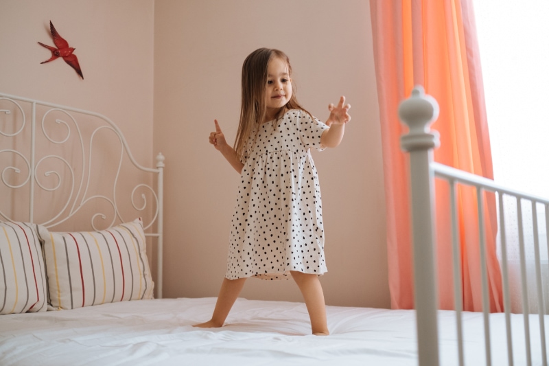 Little girl dancing on bed in her room, representing what you should know about air handlers.