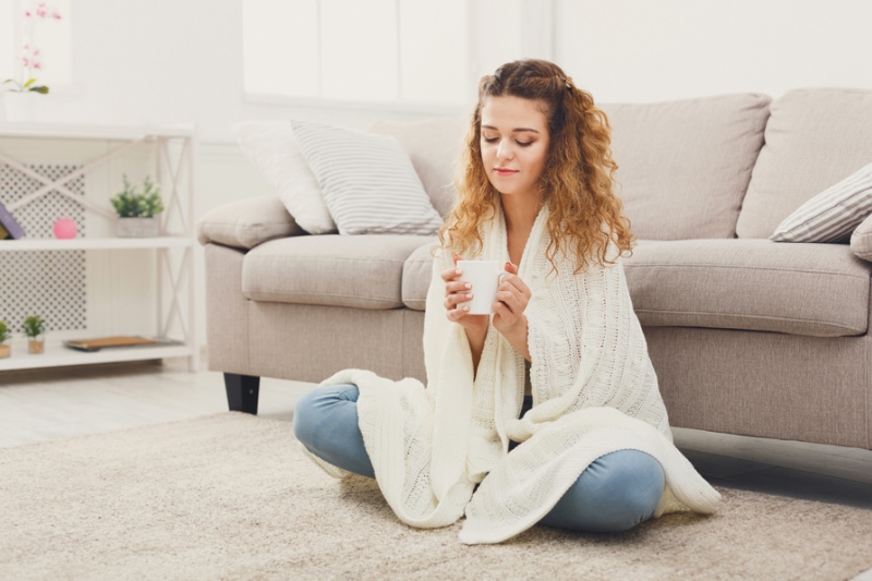 Young woman sitting on floor in Wasilla, AK, home, enjoying the improved indoor air quality.