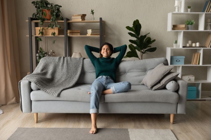 Female homeowner sitting on couch, enjoying her home's indoor air quality.