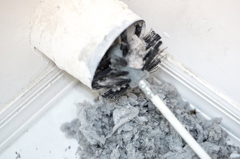 HVAC technician performing a dryer vent cleaning in Wasilla, AK.